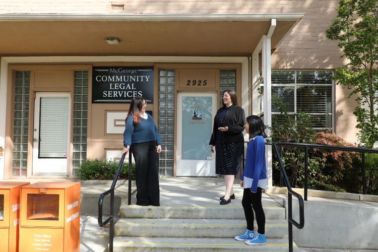 Three students speak to each other on the steps of the clinic building